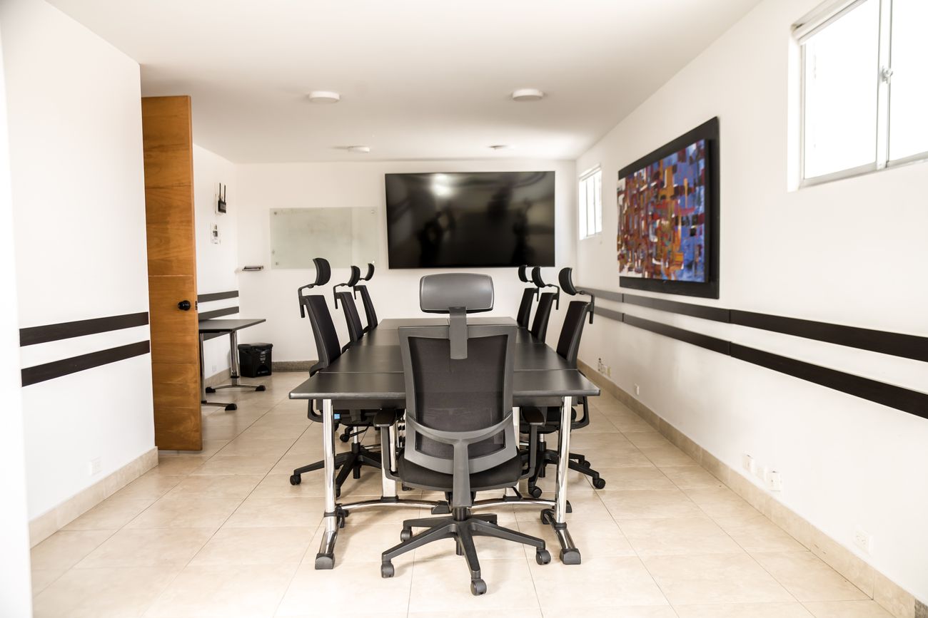 Sala de reuniones con mesa central y pantalla